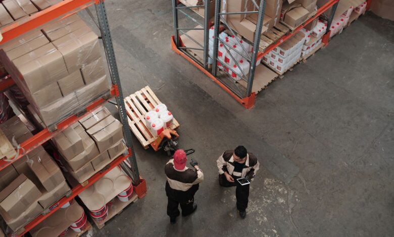 Workers in high-visibility vests inside a large industrial warehouse facility