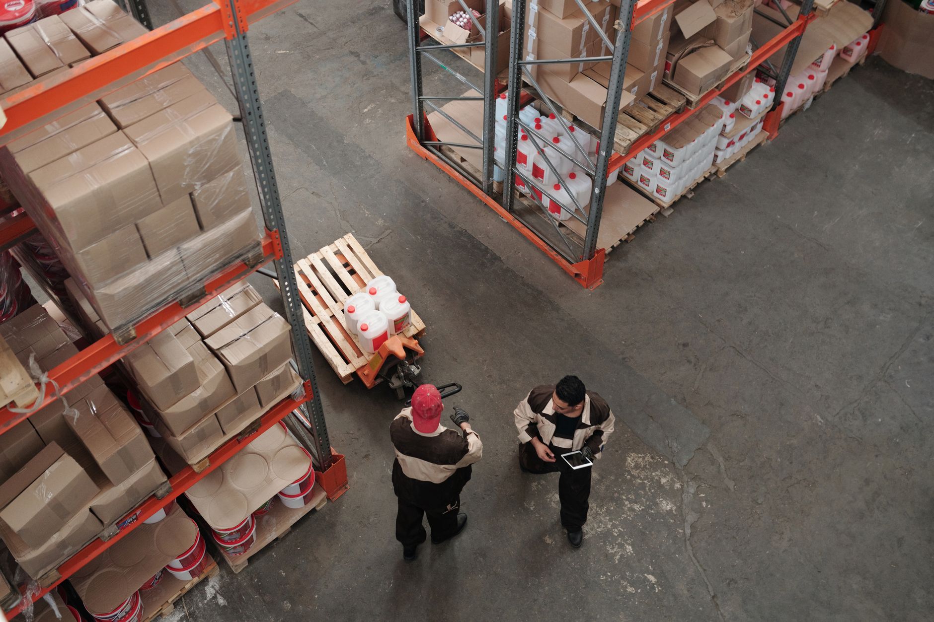 Workers in high-visibility vests inside a large industrial warehouse facility