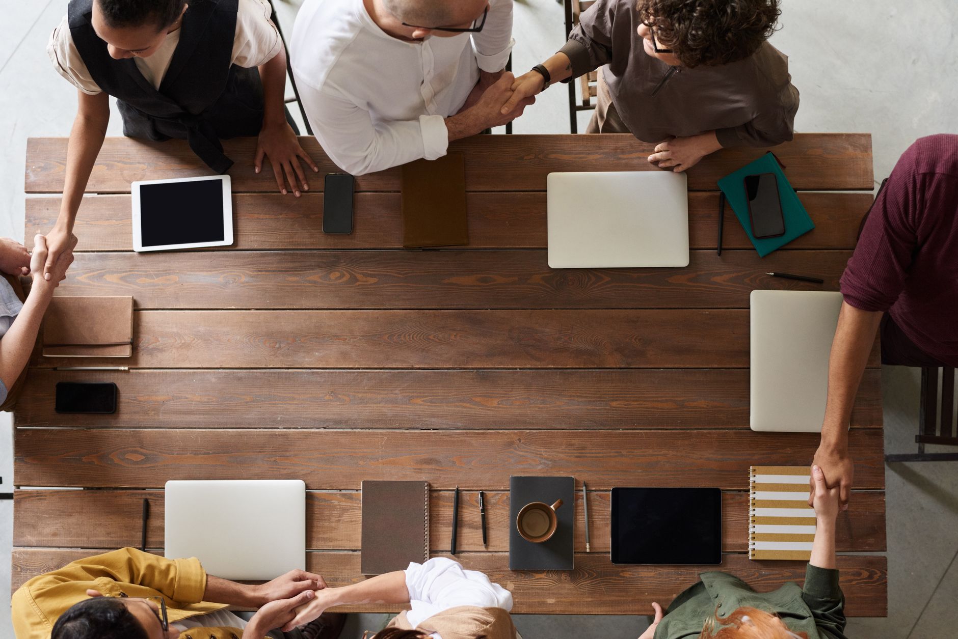 Two business professionals shaking hands across a conference table during a deal signing