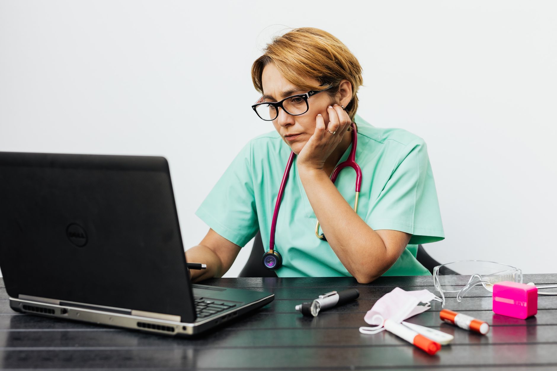 A psychiatrist conducting a remote therapy session on a laptop in a clinical office