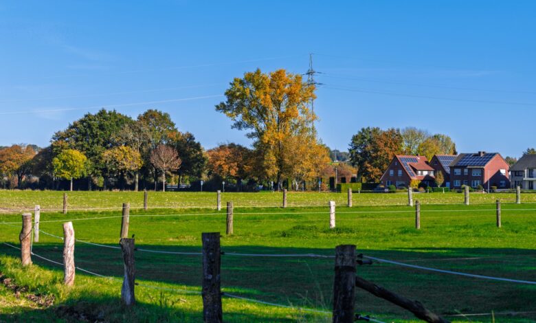 A wide rural farmland property with open fields and a distant treeline