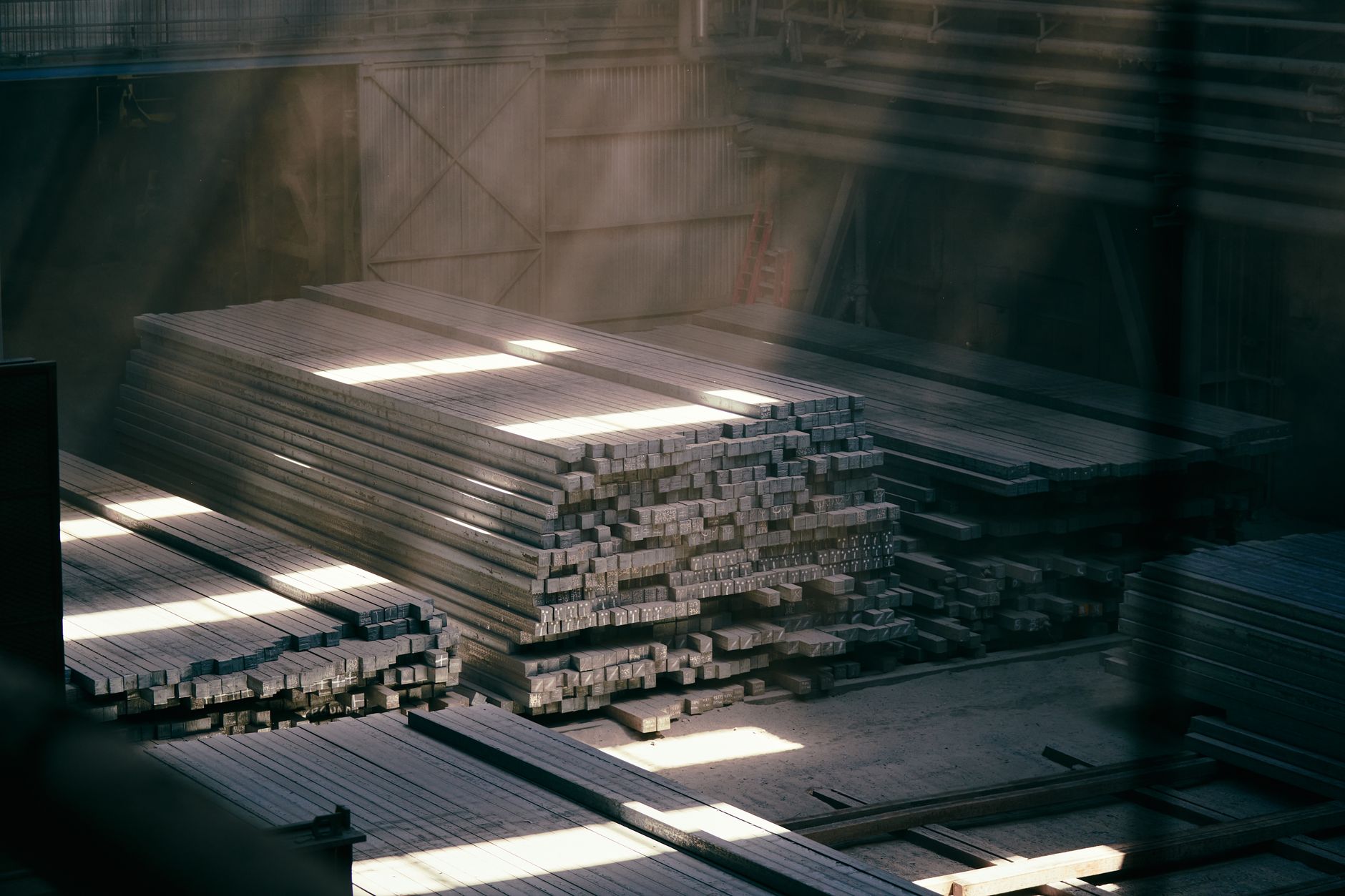 Large steel warehouse interior with stacked metal coils and industrial shelving
