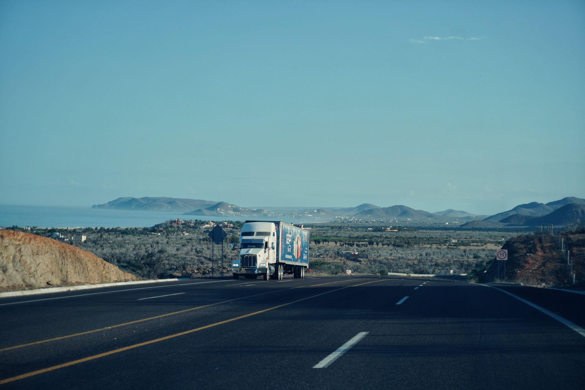 A commercial freight truck driving on a highway, representing regional shipping logistics