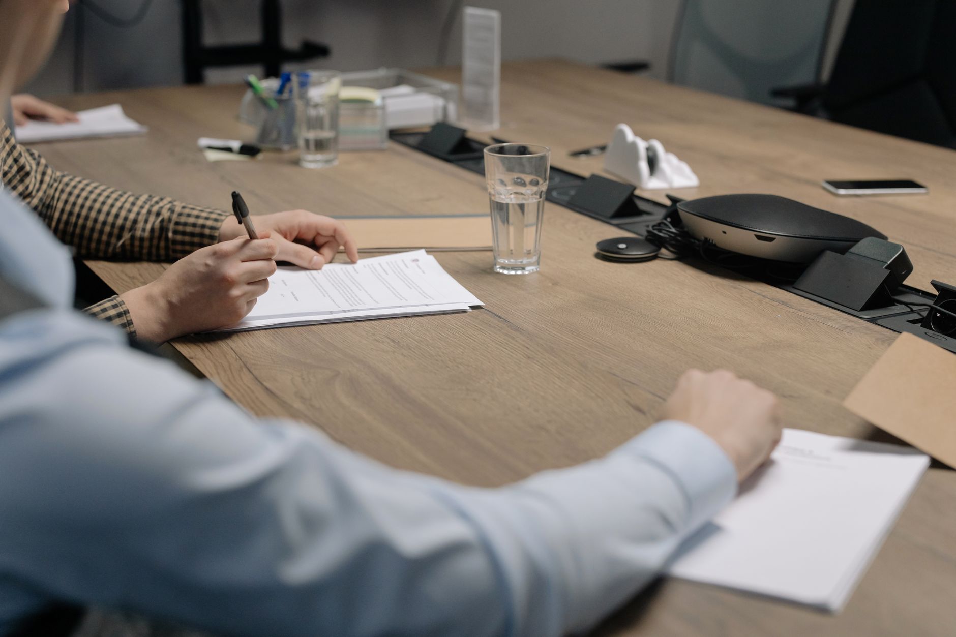 Two professionals reviewing documents at a conference table during a business negotiation