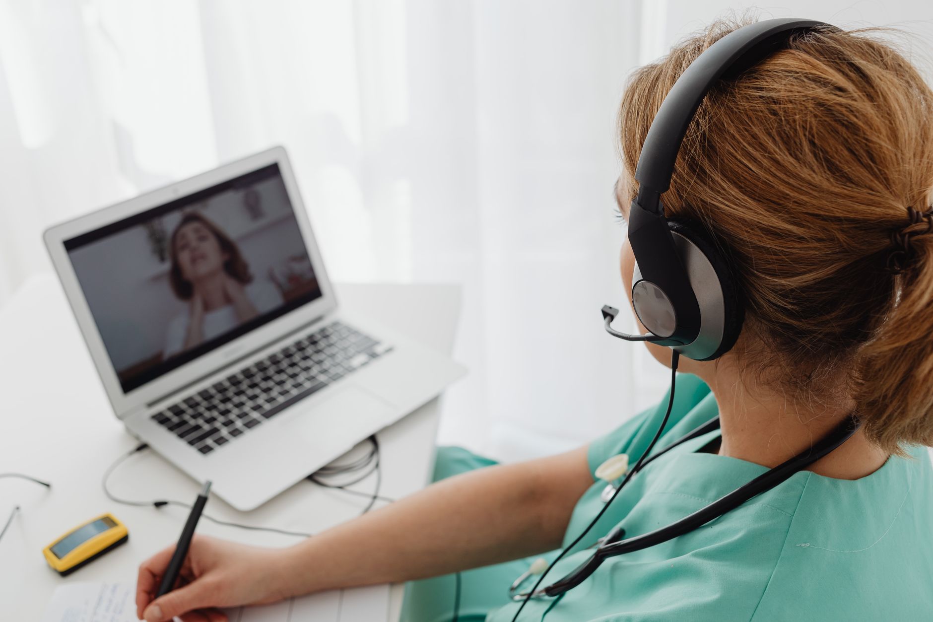 A clinician conducting a virtual telehealth appointment on a laptop