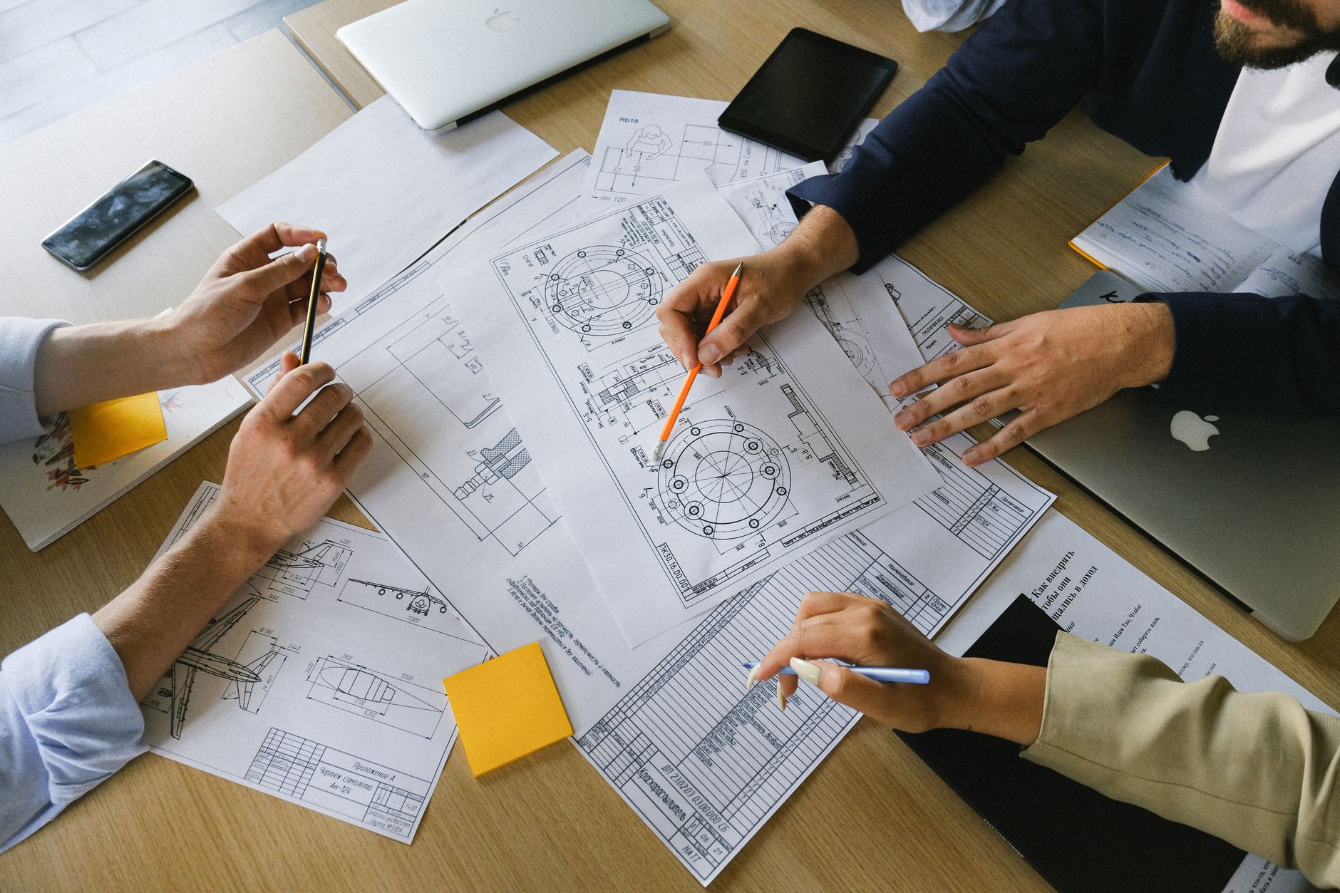 Engineers and project managers gathered around a table reviewing technical plans