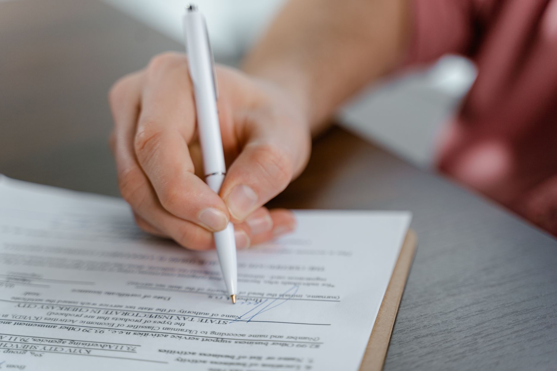 Two professionals reviewing and signing a business contract at a desk