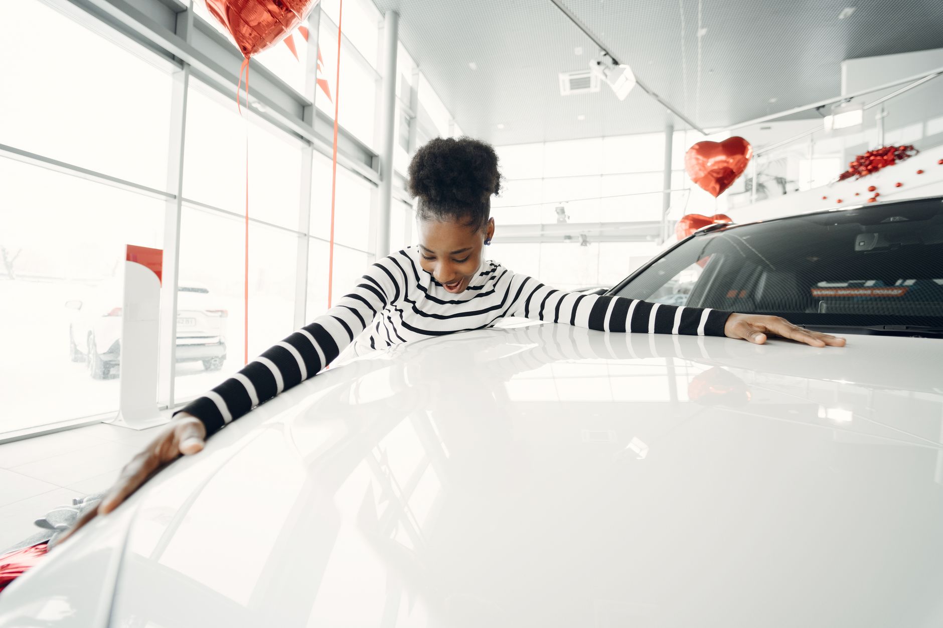 Two people shaking hands in front of a row of cars at a dealership