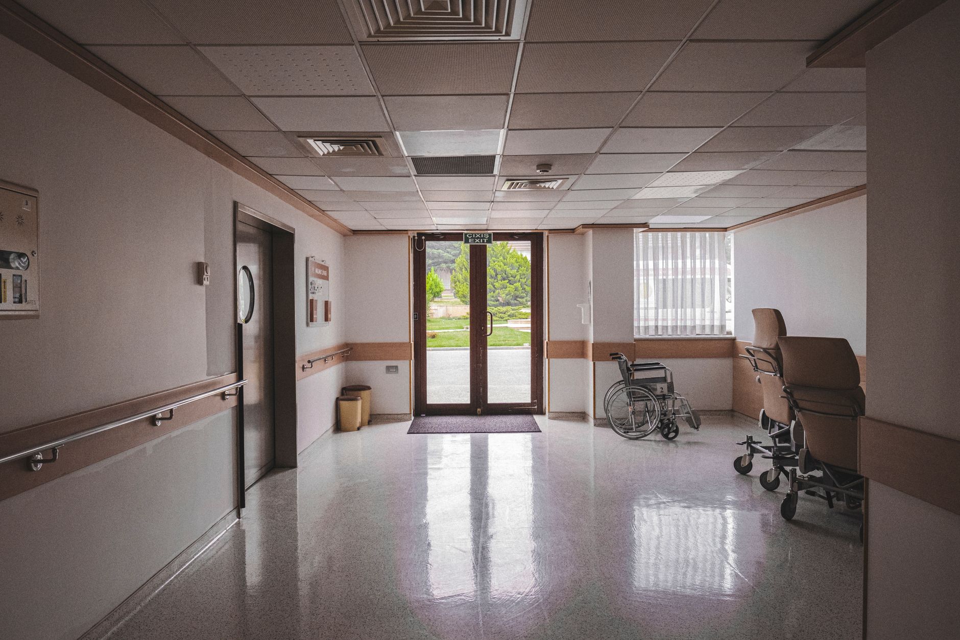 An empty hospital corridor with overhead lighting and medical facility signage