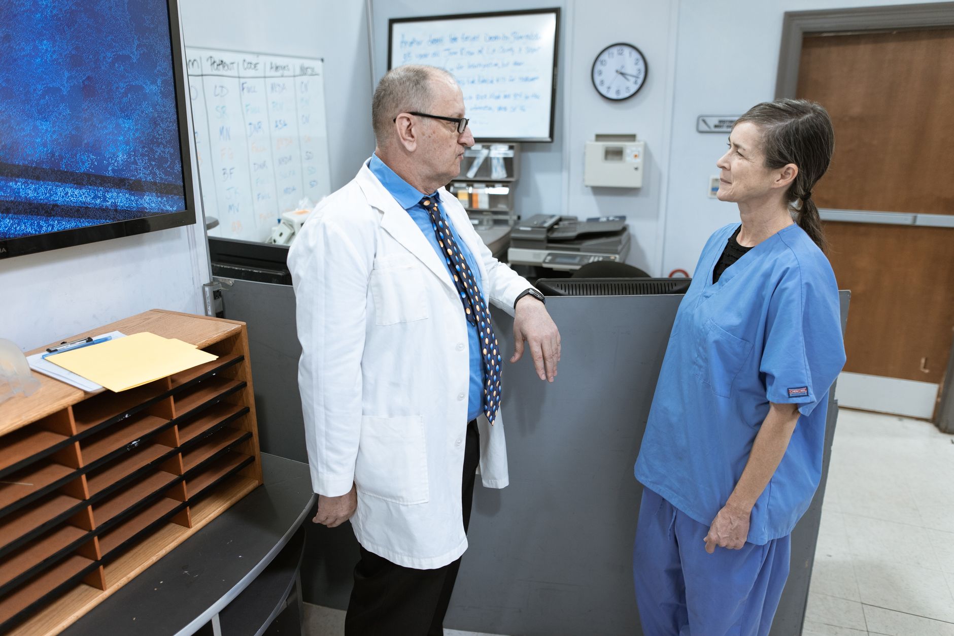 Healthcare administrator reviewing documents at a desk in a clinical office setting