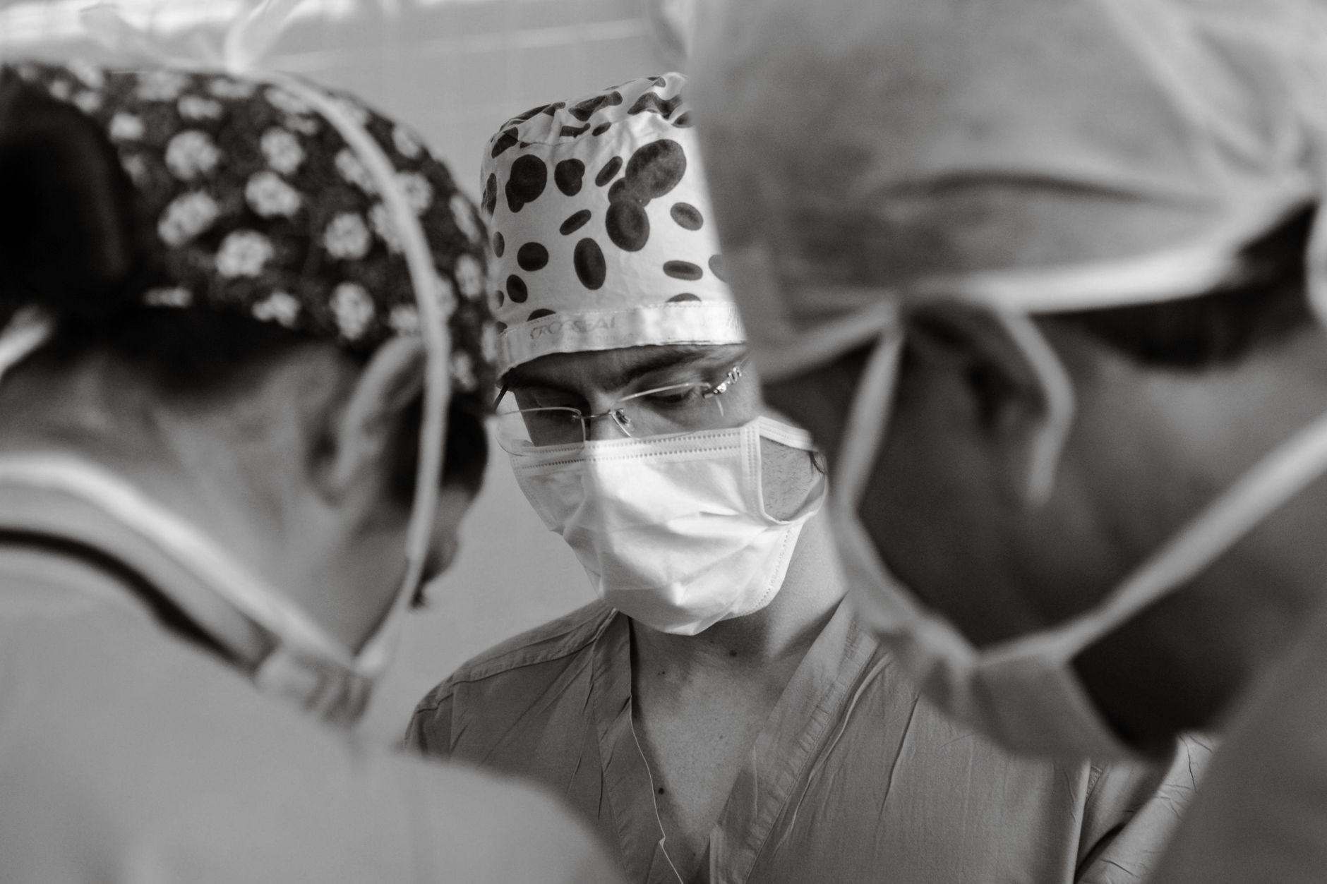 A surgeon in scrubs standing in a medical facility hallway looking thoughtful