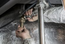 A plumber working on pipes beneath a sink in a residential home