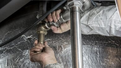 A plumber working on pipes beneath a sink in a residential home
