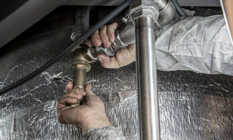 A plumber working on pipes beneath a sink in a residential home