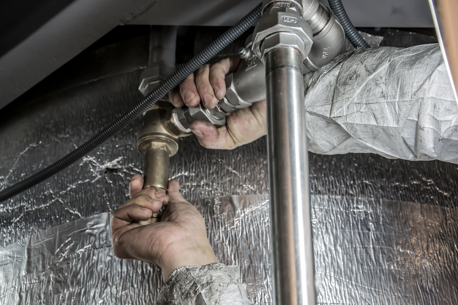 A plumber working on pipes beneath a sink in a residential home