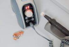 A dental laboratory technician working on prosthetic dental pieces at a workbench