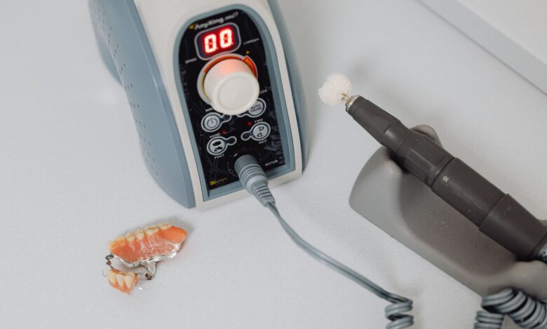 A dental laboratory technician working on prosthetic dental pieces at a workbench
