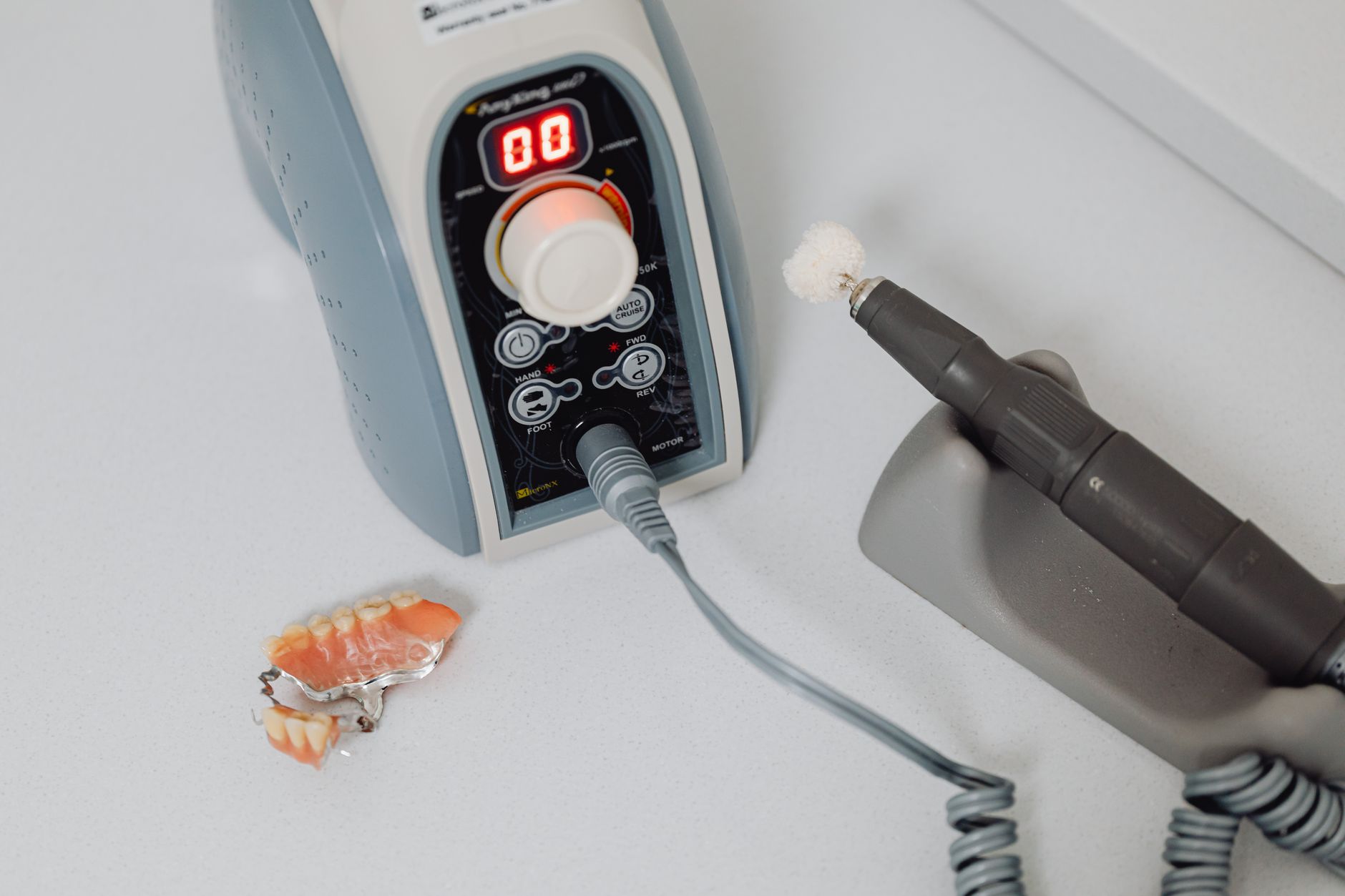 A dental laboratory technician working on prosthetic dental pieces at a workbench