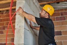 Electrician working on commercial wiring panel at a job site