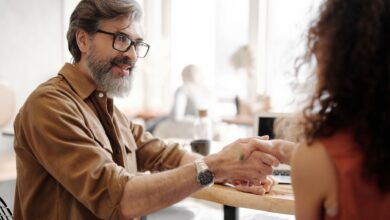 Two professionals shaking hands at a business meeting, representing an acquisition deal
