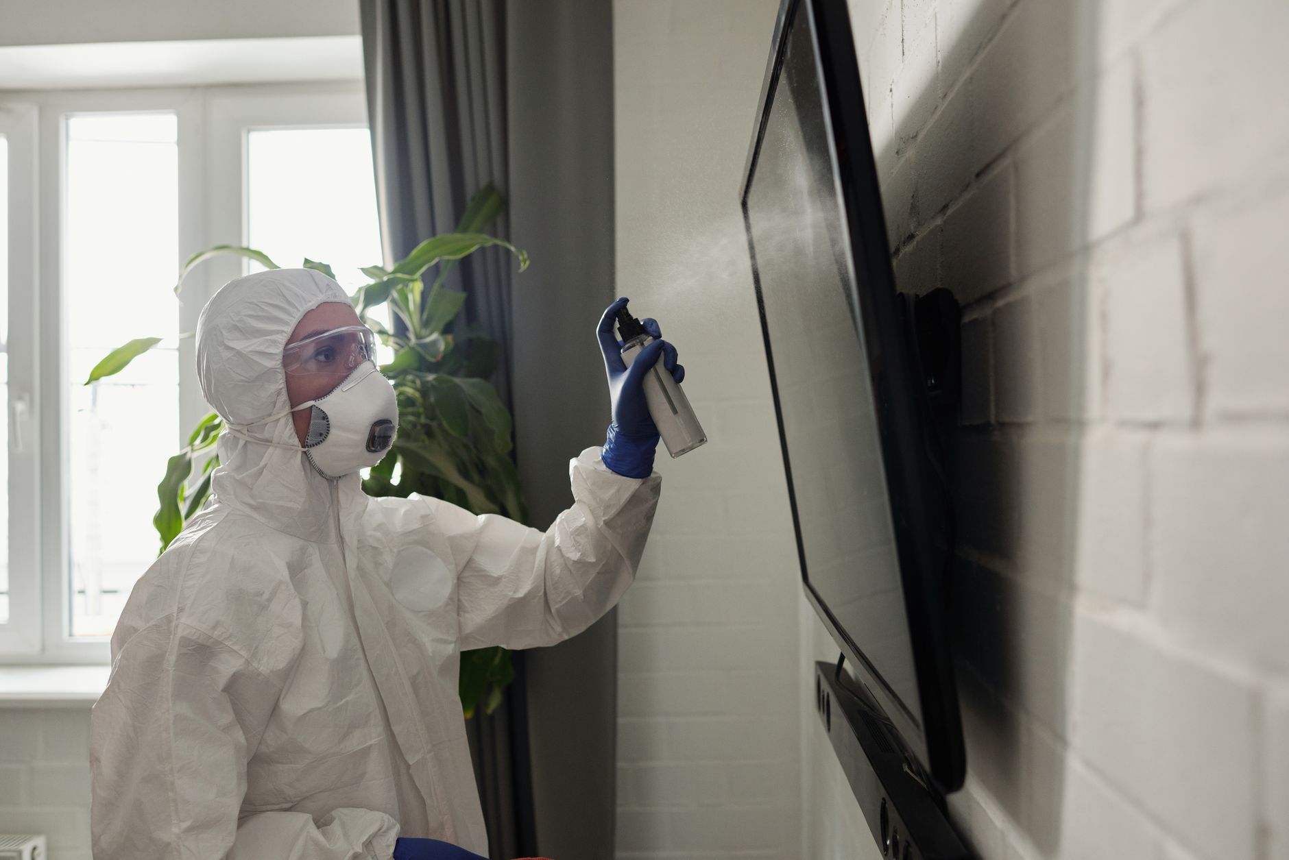 A pest control technician in protective gear treating the exterior of a house