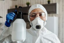 A pest control technician in uniform preparing equipment outside a residential home