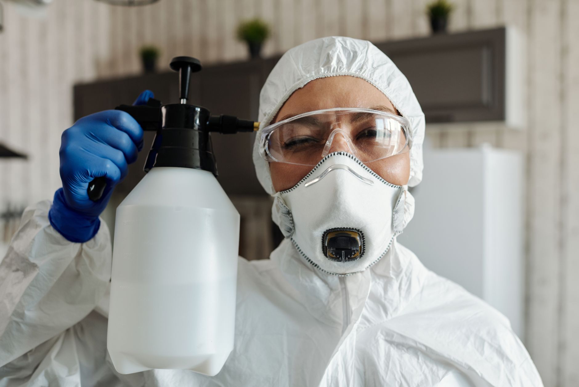 A pest control technician in uniform preparing equipment outside a residential home