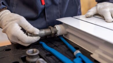 A plumber working on pipes beneath a sink in a residential home