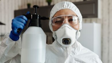 A pest control technician in uniform preparing equipment outside a residential home