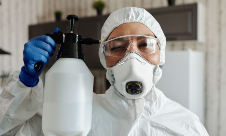 A pest control technician in uniform preparing equipment outside a residential home