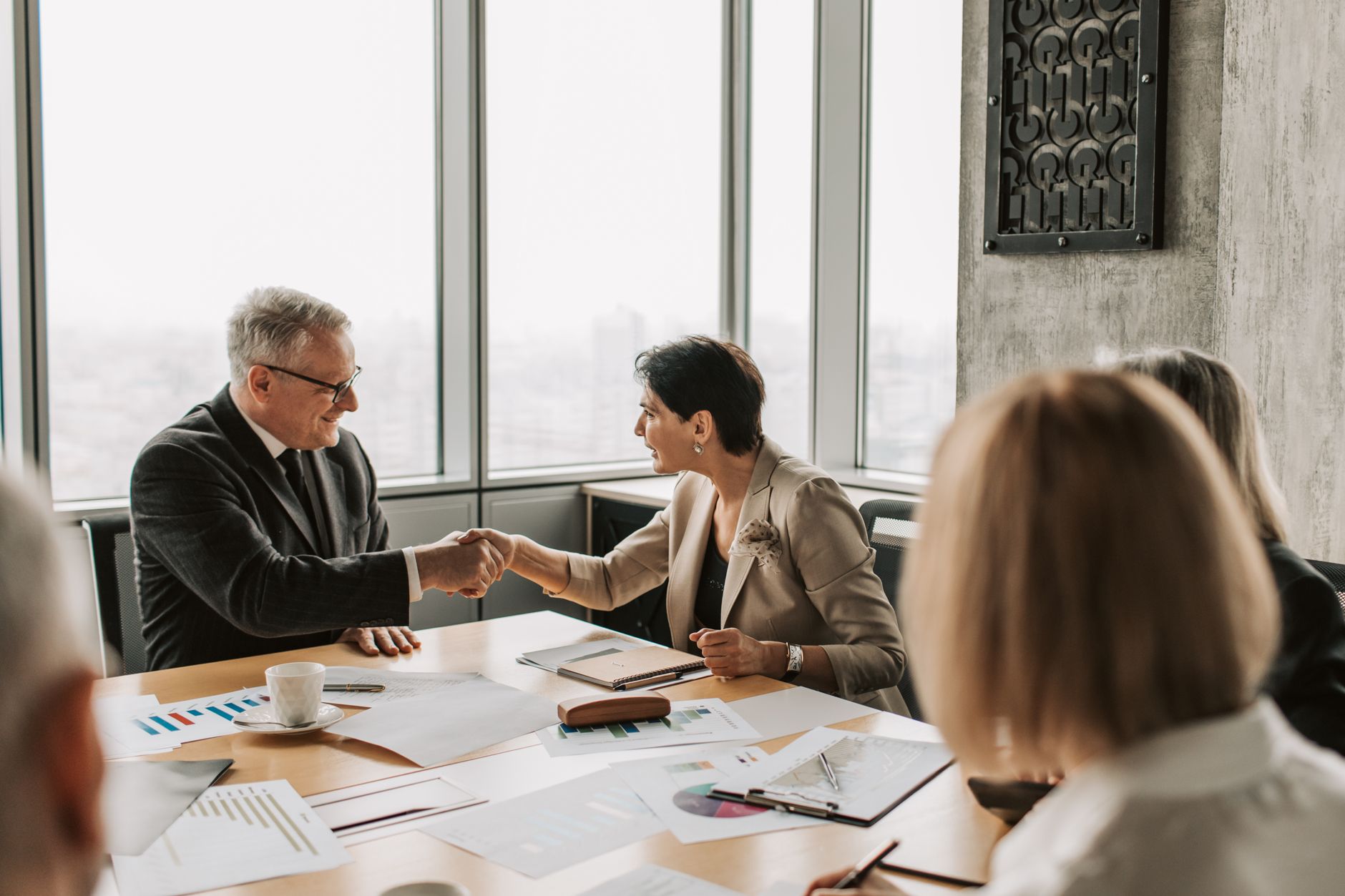 Two professionals reviewing documents at a conference table during a business deal