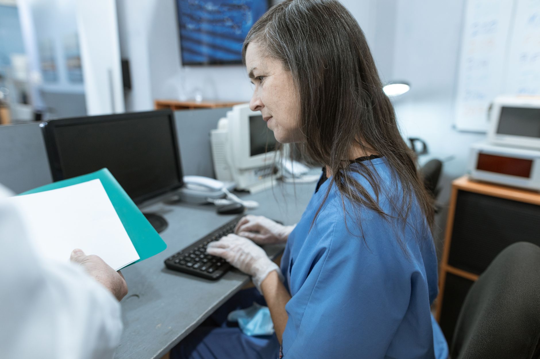 Medical facility administrator working at a desk with paperwork and computer